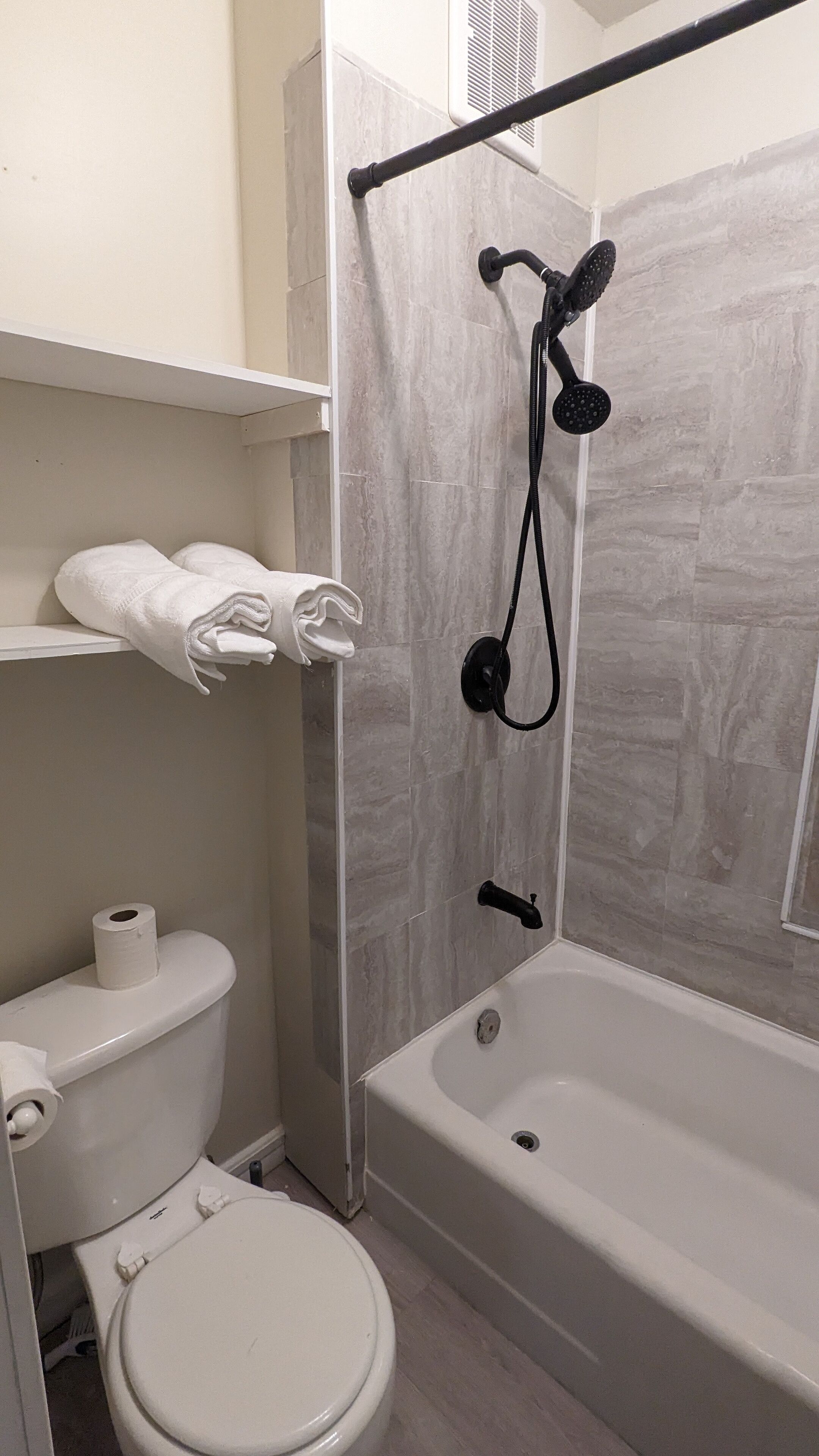 A bathroom with a toilet, a bathtub, and a shower area.