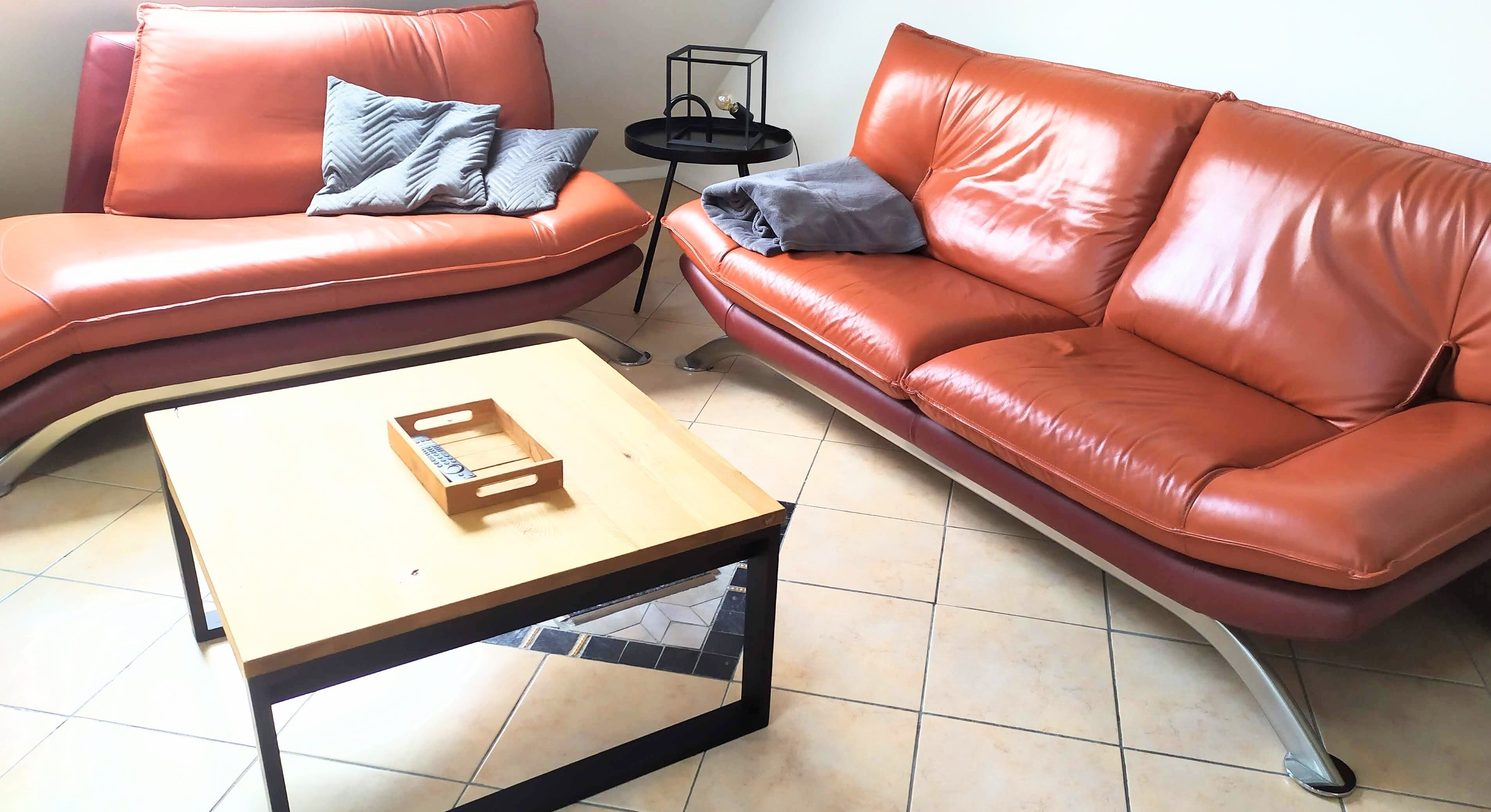 A living room with two brown leather sofas, a wooden coffee table, and a small black side table with a decorative item.
