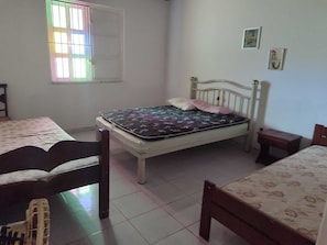 A bedroom with a single bed, a chair, a small table, and a window with a view.
