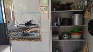 Een keuken met een centraal eiland, boven- en onderkasten gevuld met kookgerei, en een betegelde spatwand.