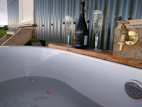 A bathtub with a wooden shelf holding a wine bottle and two glasses. - The Musterer's Hut, Outdoor Bath & Valley View (Carmarthen)