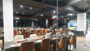Una sala de conferencias con varias mesas y sillas, separadores de vidrio y un diseño moderno de techo.