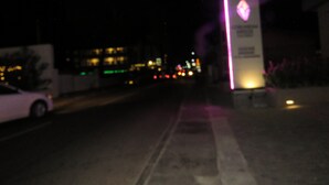 Vista nocturna de una calle con un edificio que tiene un letrero de neón.