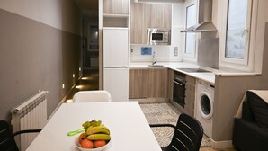 A compact kitchen with a microwave, sink, and washing machine.