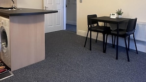 A compact kitchen with a built-in washer, a dining area with a table and chairs, and a door leading to another room.