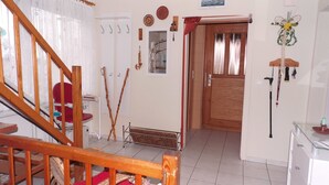 A room with a wooden staircase, a red chair, a radiator, and a door with a glass panel. - Ferienwohnung, Besonders für Familien im Oderbruch (Oderaue)
