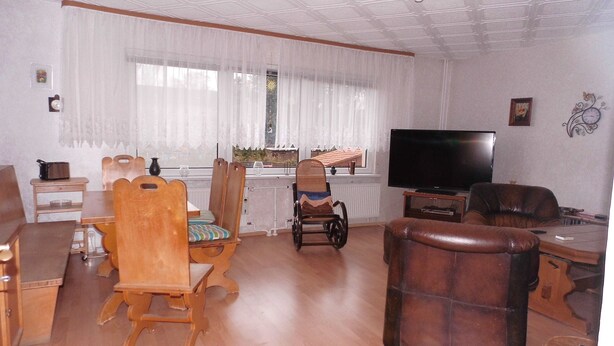 A living room with a wooden dining table, chairs, a television, and a sofa. - Ferienwohnung, Besonders für Familien im Oderbruch (Oderaue)