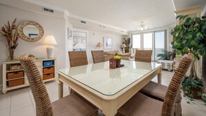 Un coin repas avec une table à plateau en verre, des chaises en osier et un buffet.