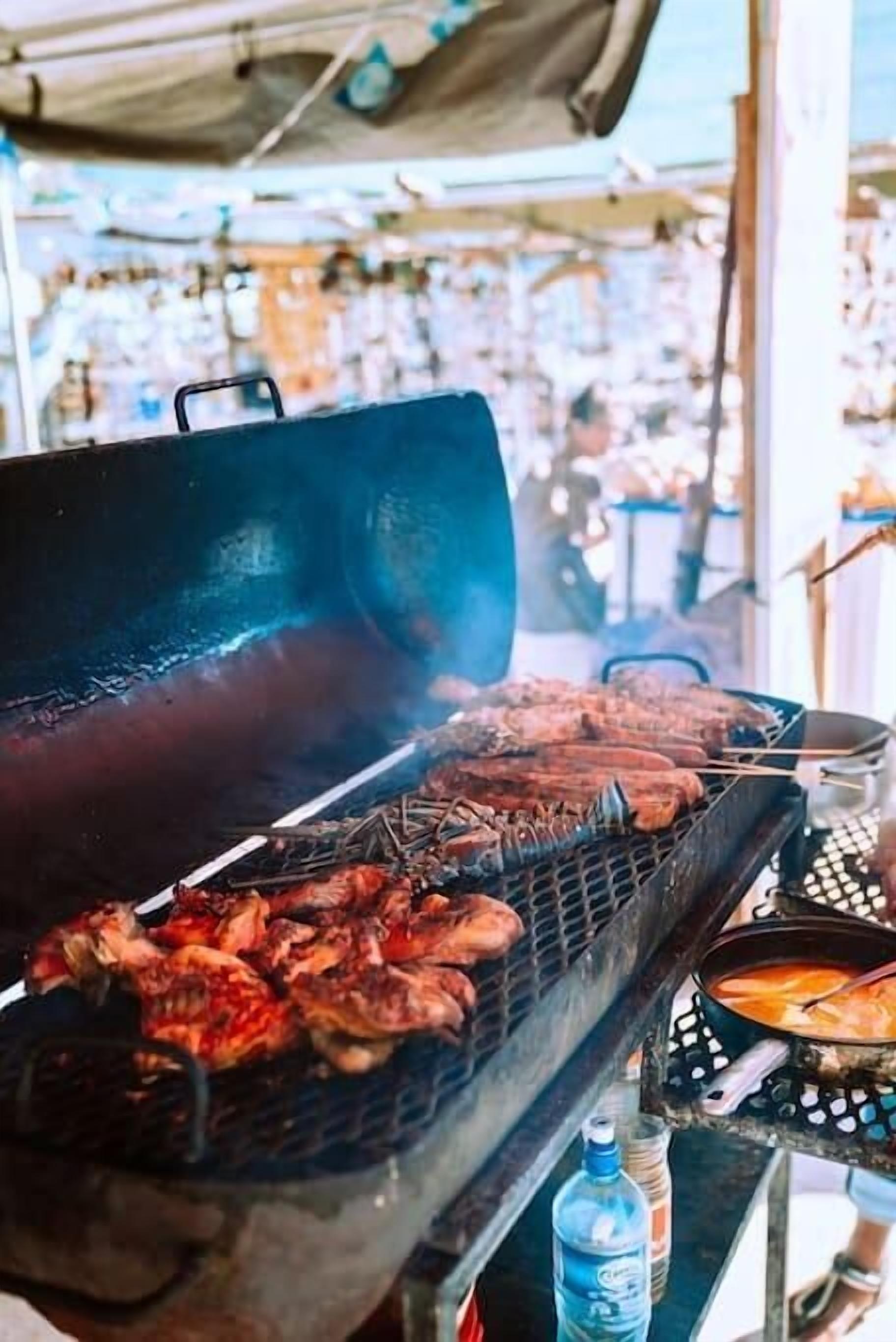 Una parrilla con diferentes carnes asándose al aire libre.