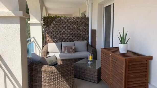 Ein Balkon mit Korbmöbeln, einer Couch und einem kleinen Tisch.