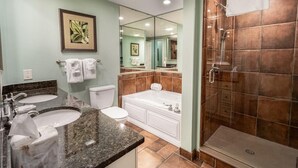 Un baño con dos lavamanos, un inodoro, una bañera y una ducha con mampara de vidrio.