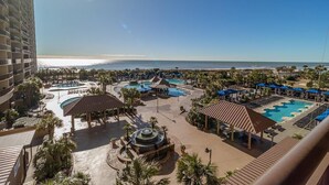 Un resort con varias piscinas, una fuente central y vista al mar.
