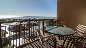Un balcón con vista a una piscina y al área del resort, amueblado con una mesa redonda y sillas.