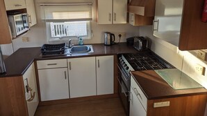 Une petite cuisine équipée comprenant un évier, une cuisinière, un grille-pain et des placards.