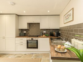 A modern kitchen with white cabinets, a built-in oven, a microwave, and a sink. There are decorative items on the counter and a framed picture on the wall.