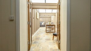 A hallway with a dining area at the end, featuring a table and chairs, and a sofa. - The Apple Loft at Jordan House (Weymouth)