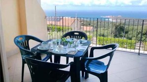 Ein Balkon mit Tisch für Zwei, mit Blick auf eine Küstenlandschaft.