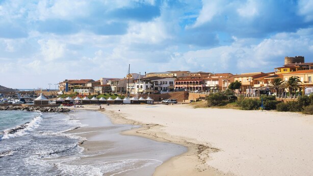 Eine Küstenstadt mit sandigem Strand, Gebäuden mit Balkonen und einer Turmkonstruktion.