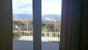 Ein Balkon mit Blick auf das Meer und entfernte Gebäude.