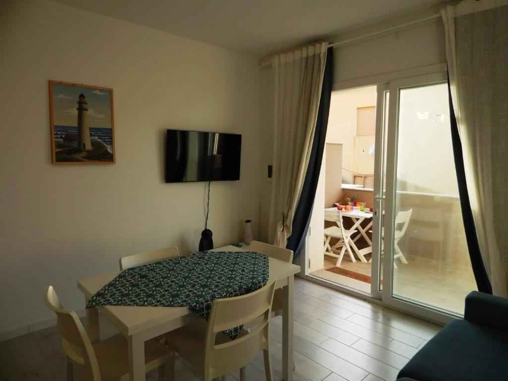 En matplats med ett bord och stolar, en platt-TV som är monterad på väggen och utsikt över en balkong med bord och stolar.