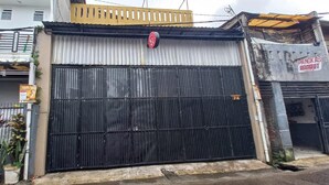 A large black metal gate with a red circular sign above it, a corrugated metal wall, and a small sign for a restaurant. - OYO 93668 Buah Batu Guest House (Bandung)