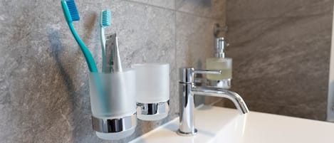 A bathroom sink with a toothbrush holder and a soap dispenser.