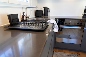 A kitchen with a stainless steel countertop, a coffee maker, and a dish rack.
