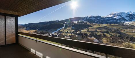Een balkon met uitzicht op een bergachtig landschap en een heldere lucht.
