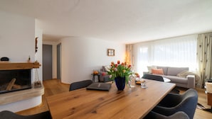 Una sala de estar moderna con una mesa de comedor de madera, una chimenea y un sofá.