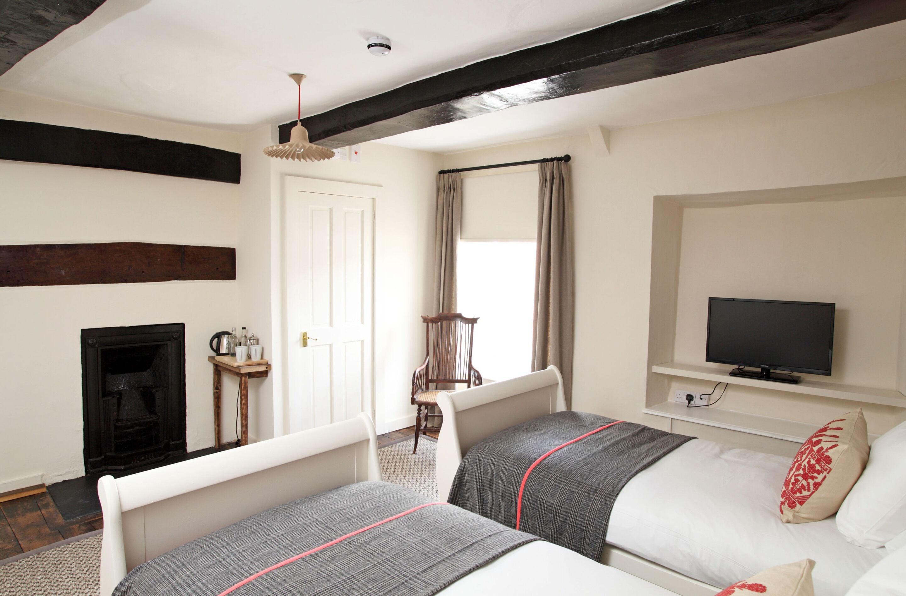 Quarto com duas camas, televisão, lareira e janela com cortinas.