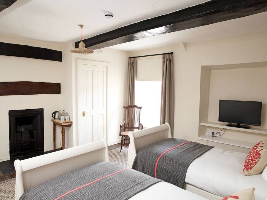 Quarto com duas camas, televisão, lareira e janela com cortinas.