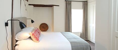 A bedroom with a bed, bedside lamp, and a small wooden stool.