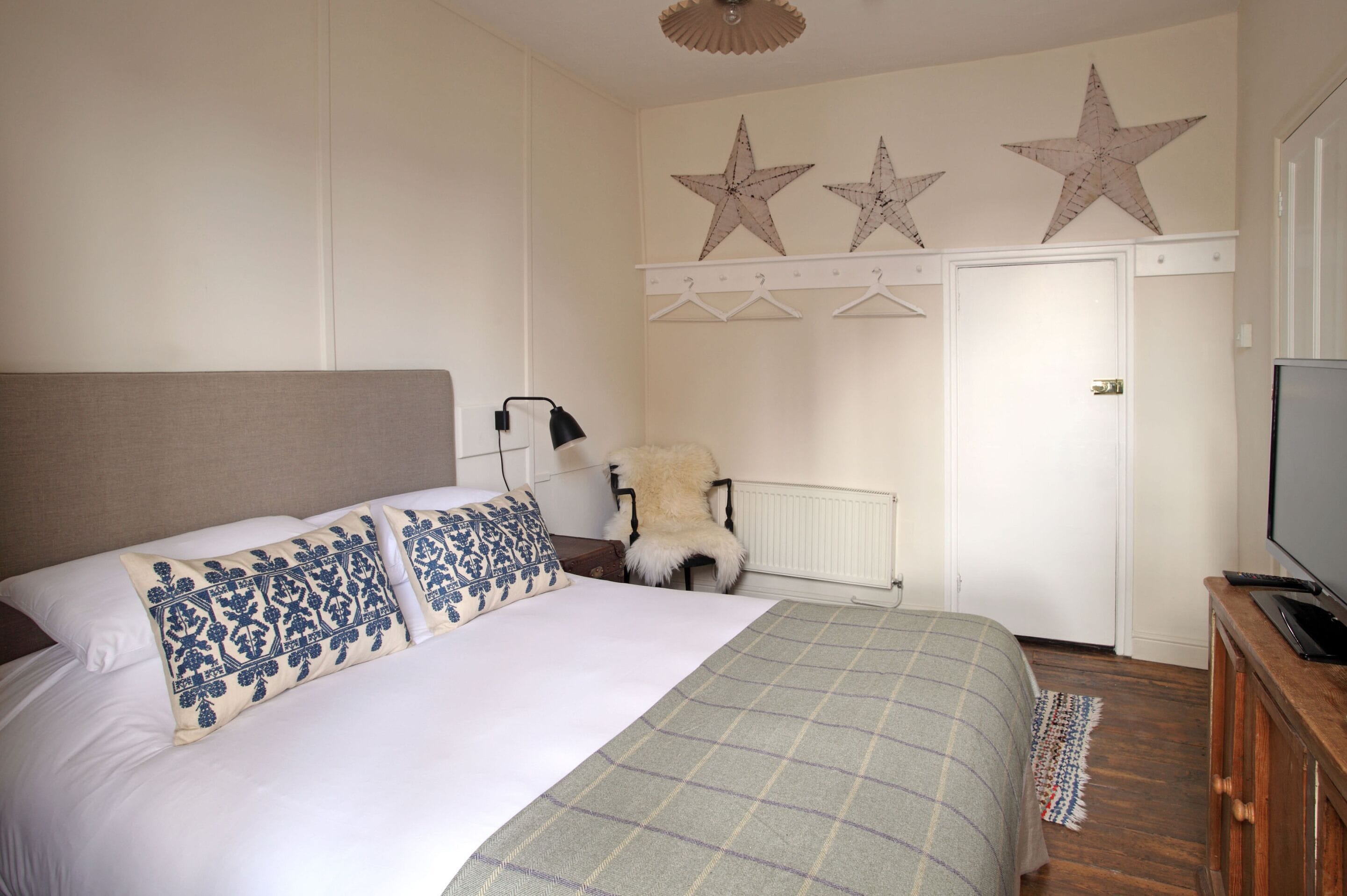 A bedroom with a bed, a chair, a television, and wall decorations.