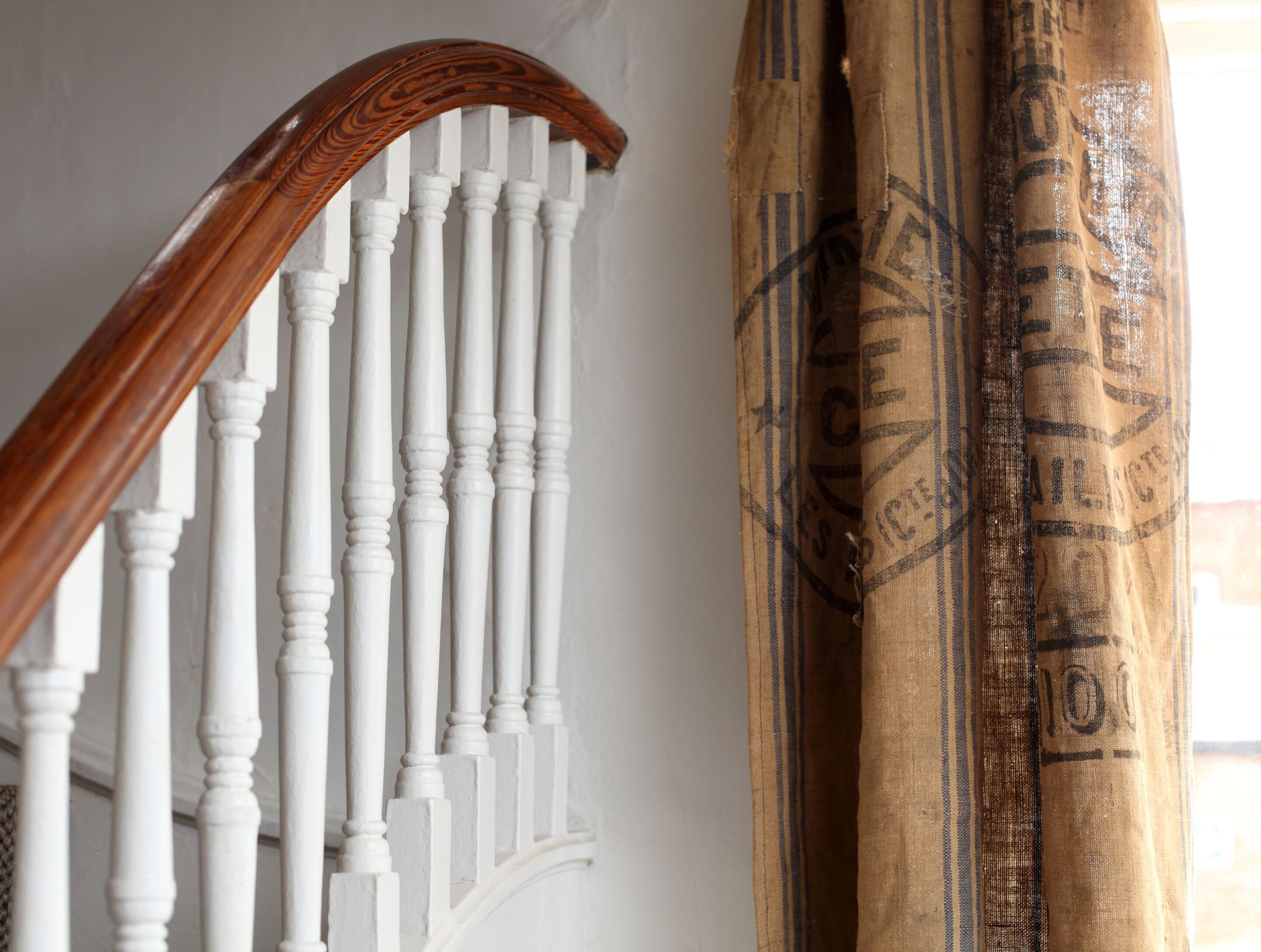 Un escalier avec des balustres blanches et une main courante en bois.