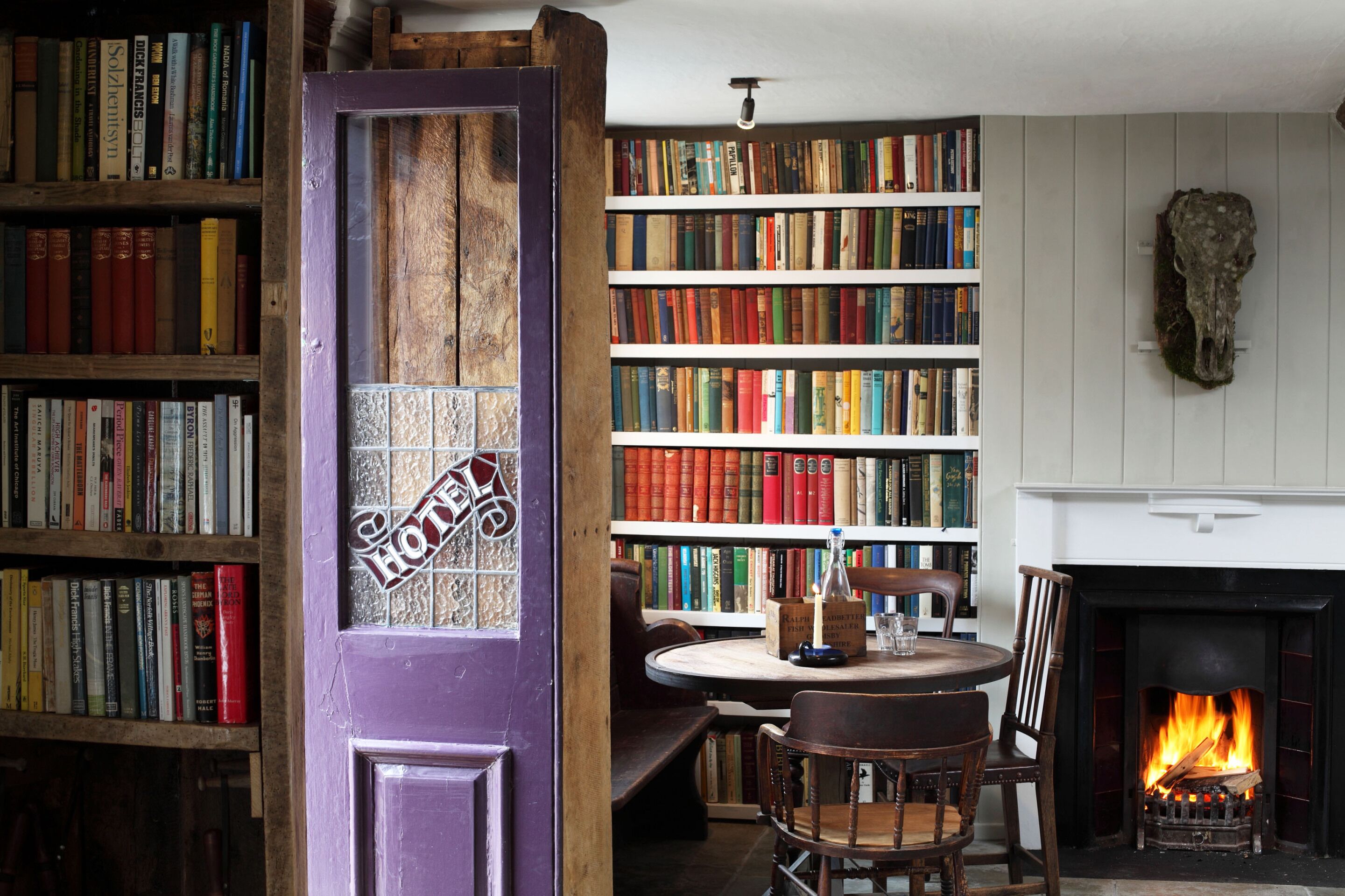 Ein gemütliches Zimmer mit Kamin, einer Bücherwand voller Bücher und einer Glastür.