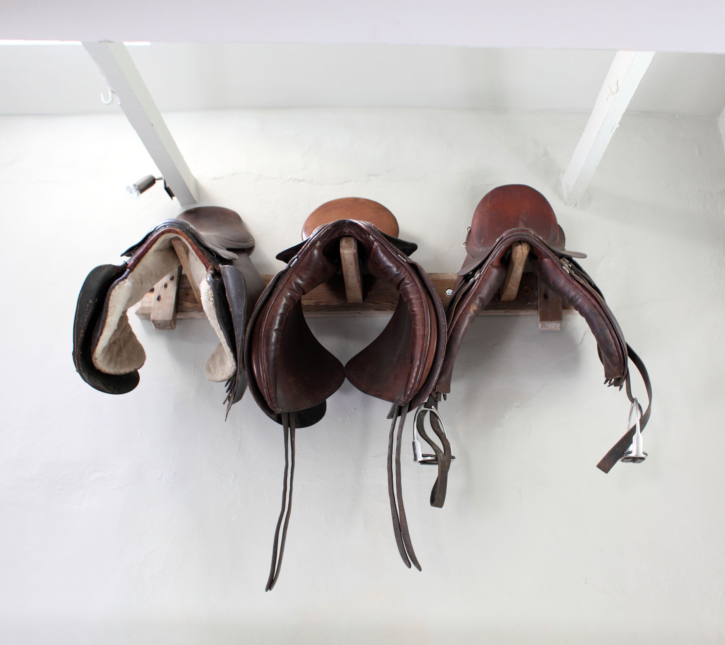 A wall-mounted rack holding several saddles.