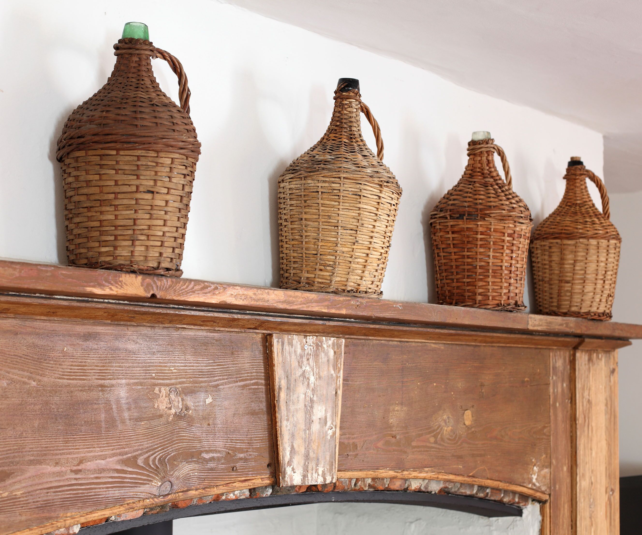 A wooden mantel with four woven baskets of varying sizes.