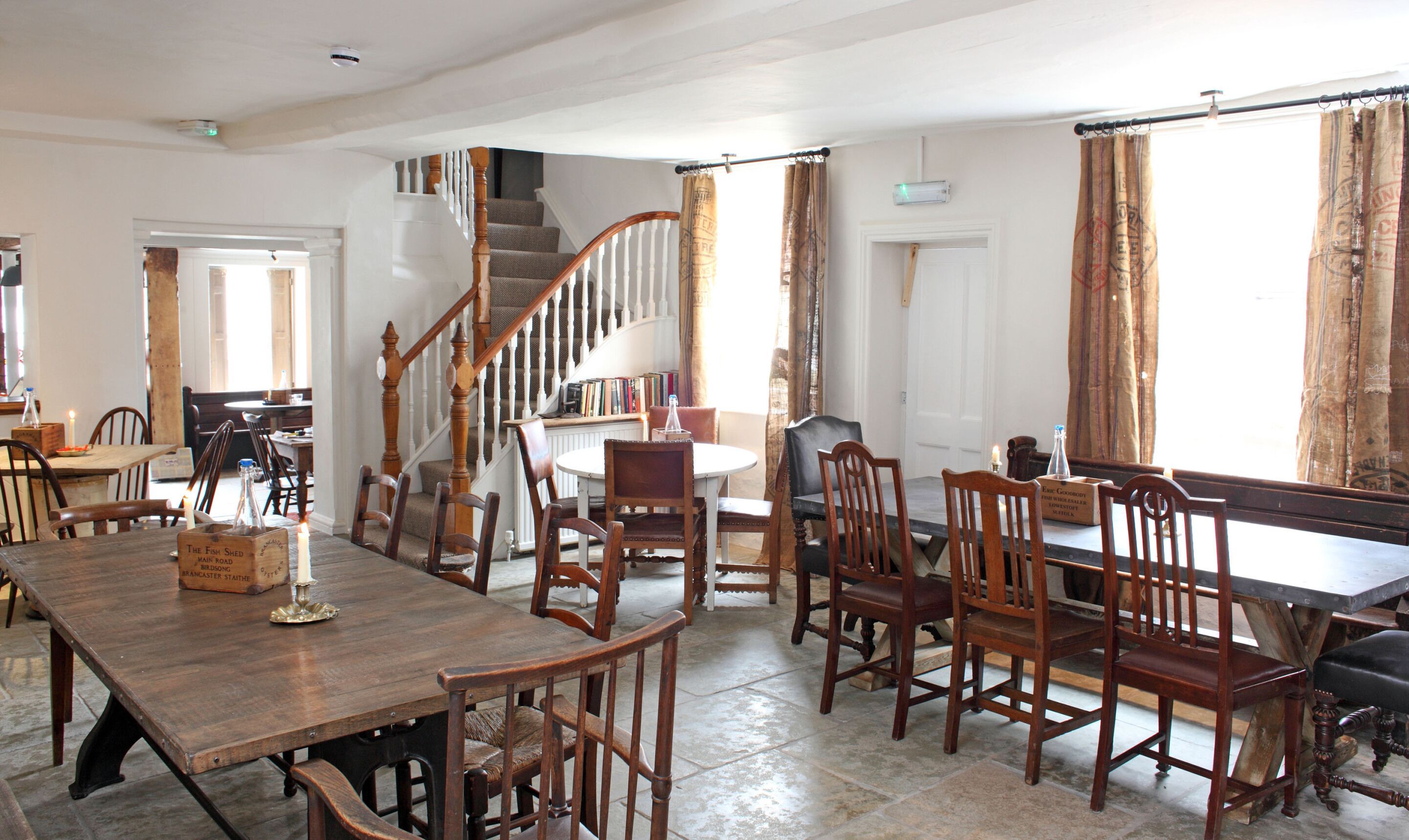 Un comedor con una mesa y sillas de madera, una escalera y estanterías.