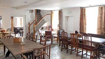 Un comedor con una mesa y sillas de madera, una escalera y estanterías.