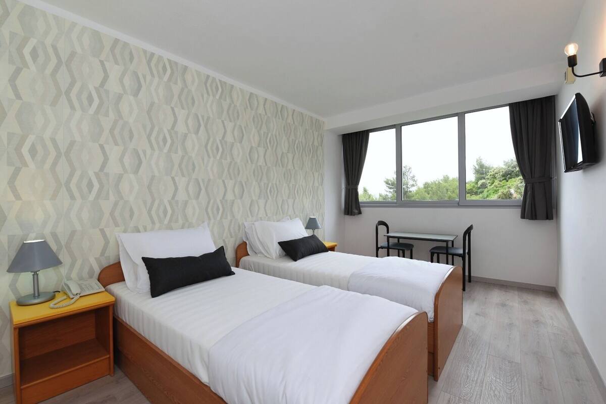 Ein Hotelzimmer mit zwei Betten, einem Schreibtisch und einem Stuhl.