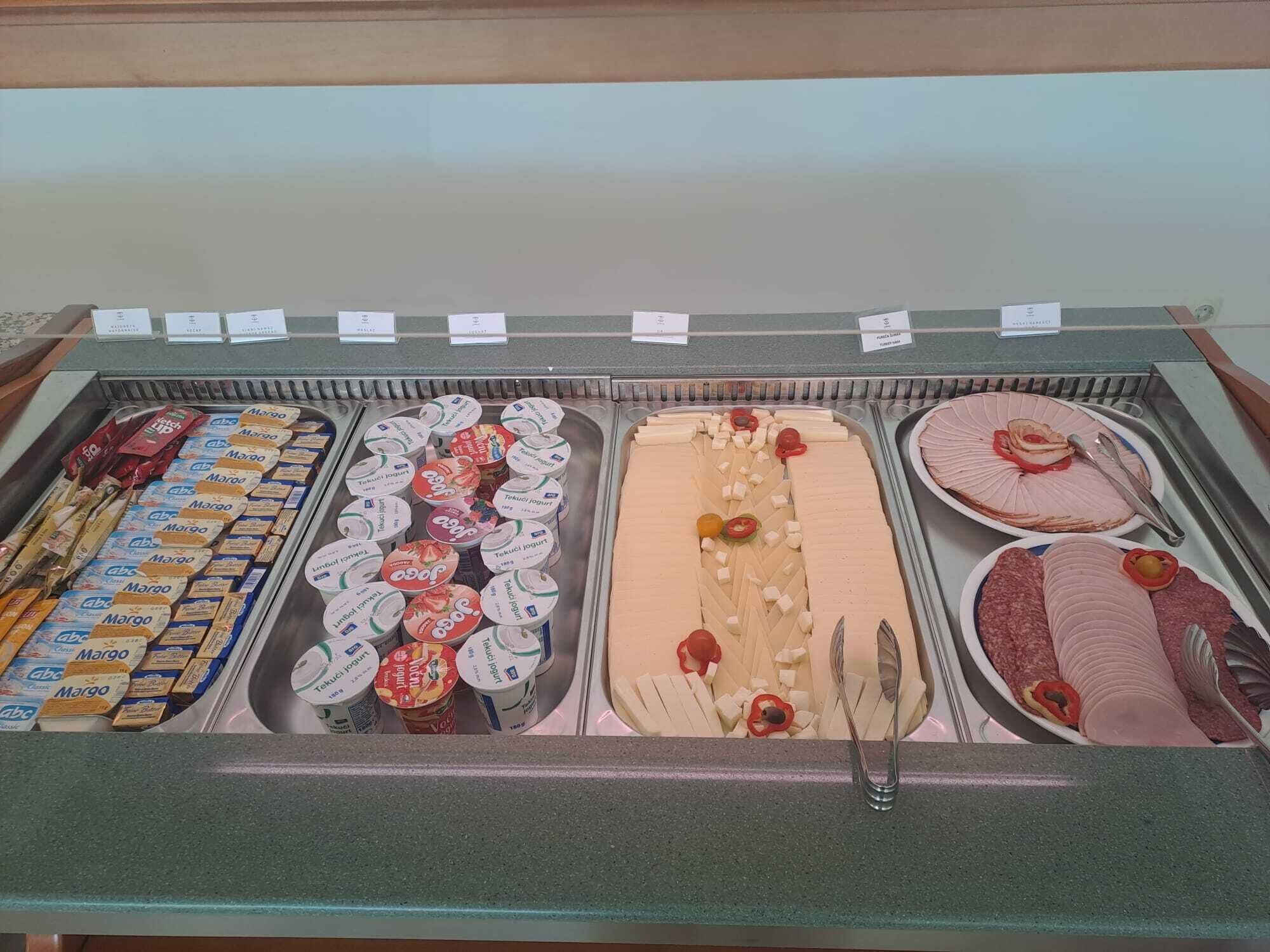 Mostrador de delicatessen con varios quesos, carnes y productos envasados.