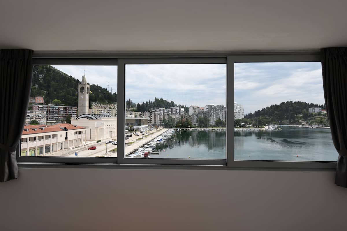 Ein Zimmer mit großem Fenster mit Blick auf einen Yachthafen, eine Kirche und eine Stadtansicht.