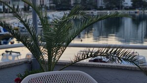 Una silla y una lámpara cerca de un cuerpo de agua, con edificios al fondo.