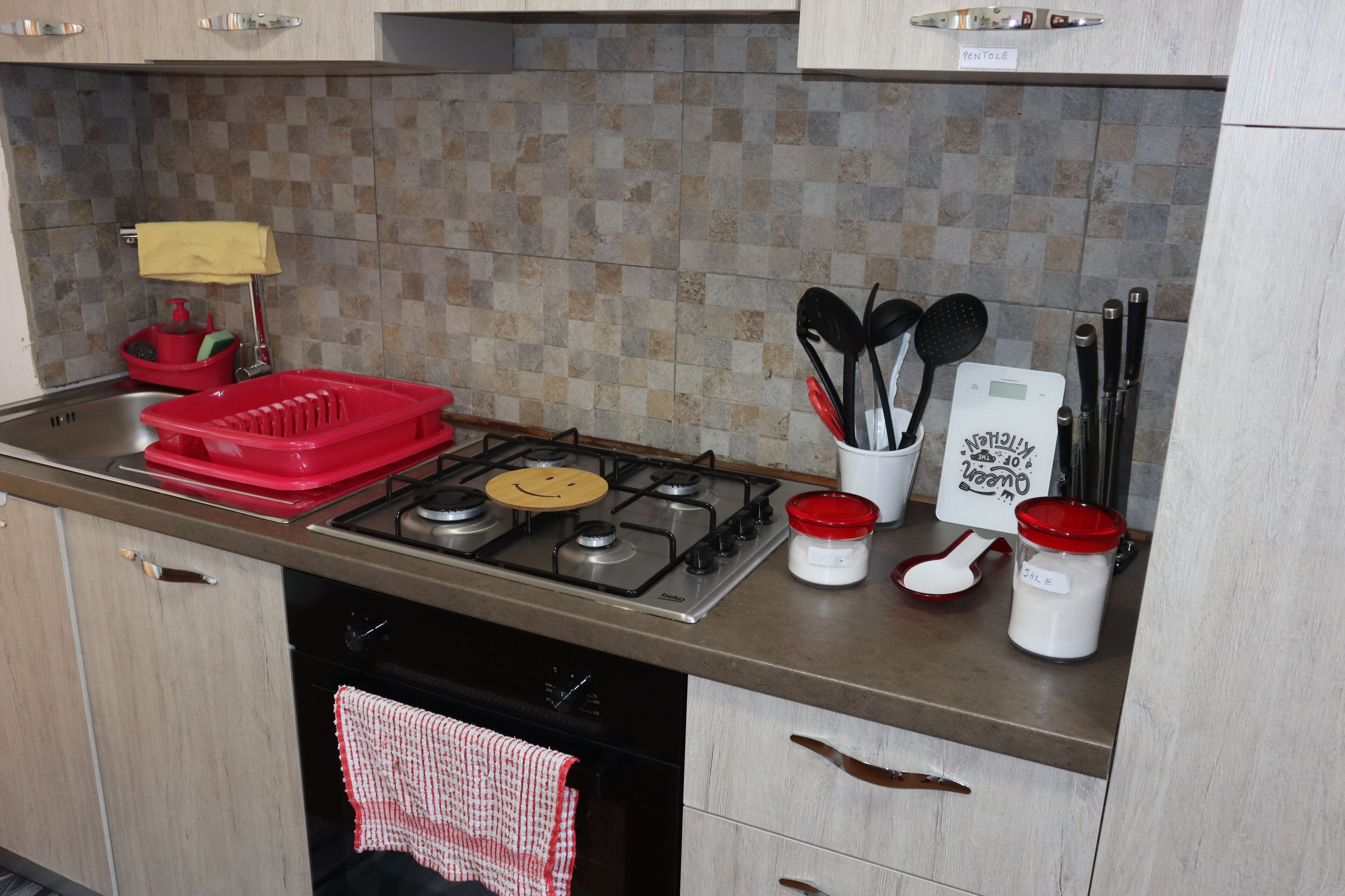 A kitchen with a gas stove, a sink, and various utensils.