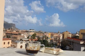 Un paisaje urbano con edificios, cielo despejado y una taza de café sobre una mesa.
