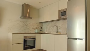 A modern kitchen with a built-in oven, stainless steel refrigerator, and a microwave. - Marina Club Adriatic, Gibraltar - Studio Apartment (Gibraltar)