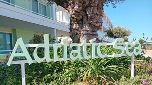 A sign for 'Adriatic Sea' with a backdrop of greenery and a building. - Marina Club Adriatic, Gibraltar - Studio Apartment (Gibraltar)