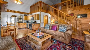 A spacious living area with a wooden staircase, a leather sofa, and a dining table. - Hot Tub ★ Pool Table ★ Firepit ★Very Private (Townsend)