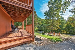A wooden deck with outdoor seating, surrounded by a forested landscape. - Hot Tub ★ Pool Table ★ Firepit ★Very Private (Townsend)