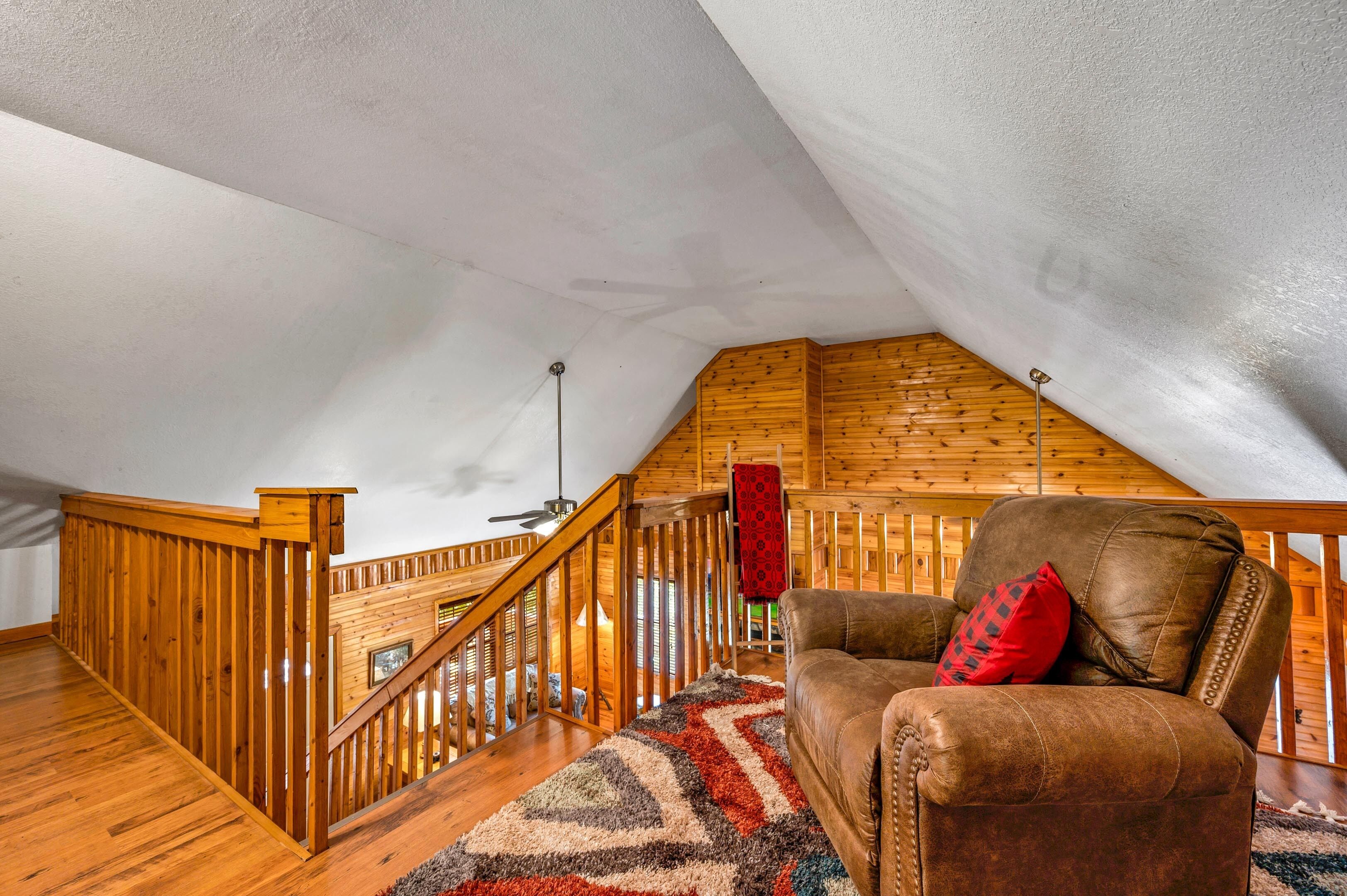 Un dormitorio estilo loft con una escalera de madera, un sofá de cuero y una alfombra estampada.